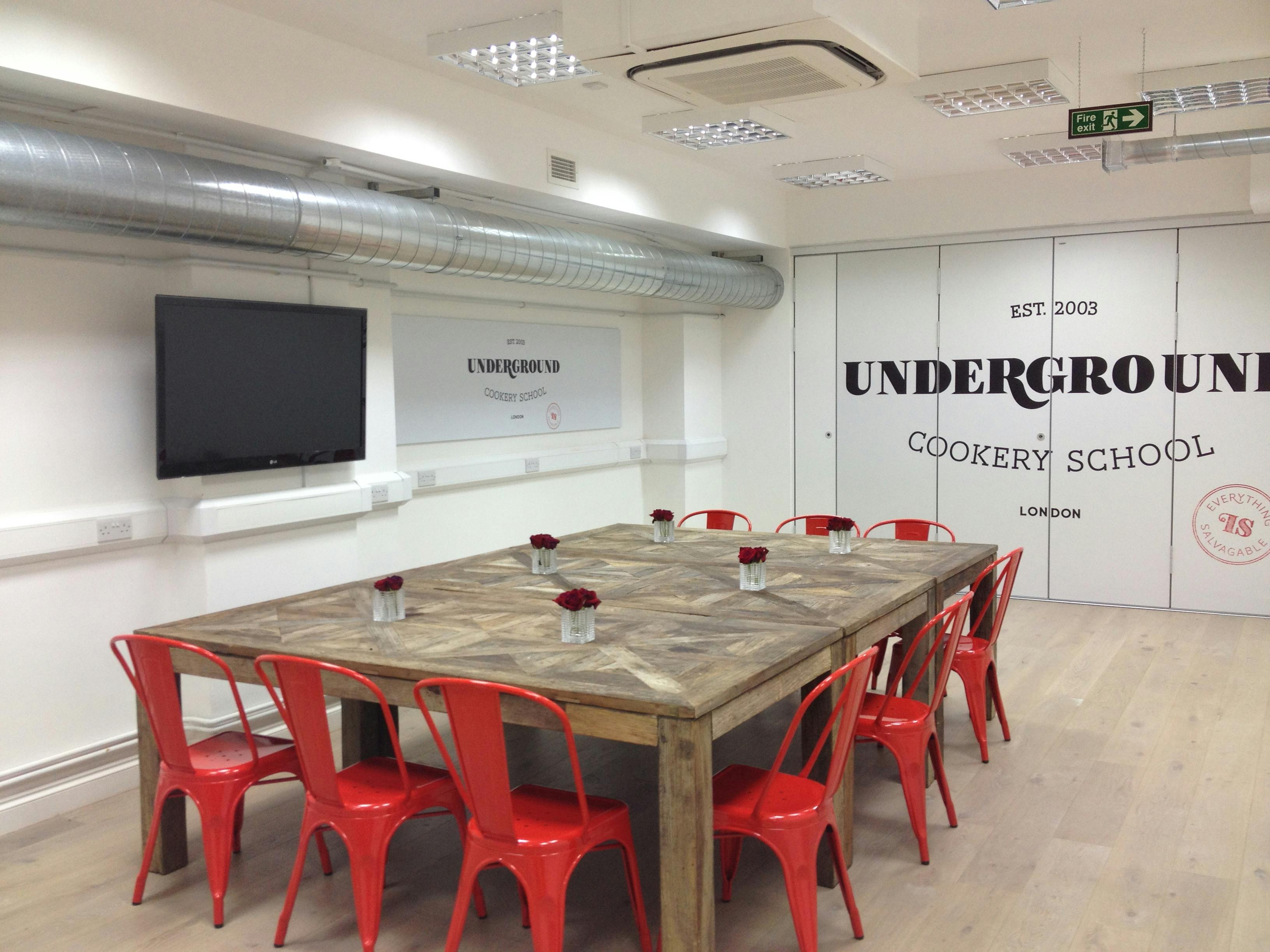 Modern meeting space with wooden table and red chairs for team-building events.